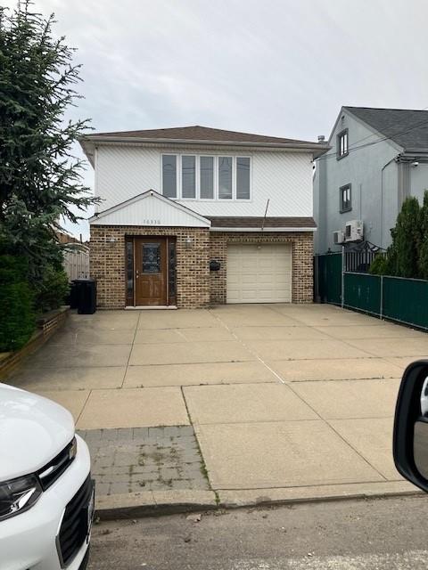 16330 95th St, Howard Beach, NY 11414 - view of front of home with brick siding, concrete driveway, and a garage