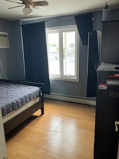 16330 95th St, Howard Beach, NY 11414 - bedroom with light wood-style flooring, baseboard heating, and a ceiling fan