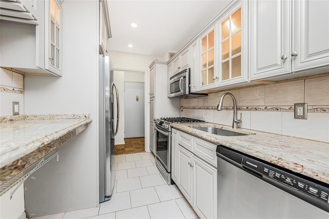 5550 Fieldstone Rd Unit 1C, Bronx, NY 10471 - kitchen with appliances with stainless steel finishes, backsplash, white cabinets, light stone counters, and glass insert cabinets