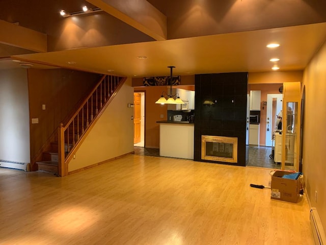 231 Willowood Dr, Wantagh, NY 11793 - unfurnished living room with baseboard heating, wood finished floors, stairway, and recessed lighting