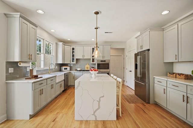 10 Inverness Ct, White Plains, NY 10605 - kitchen with appliances with stainless steel finishes, a kitchen island, backsplash, light stone countertops, and light wood finished floors