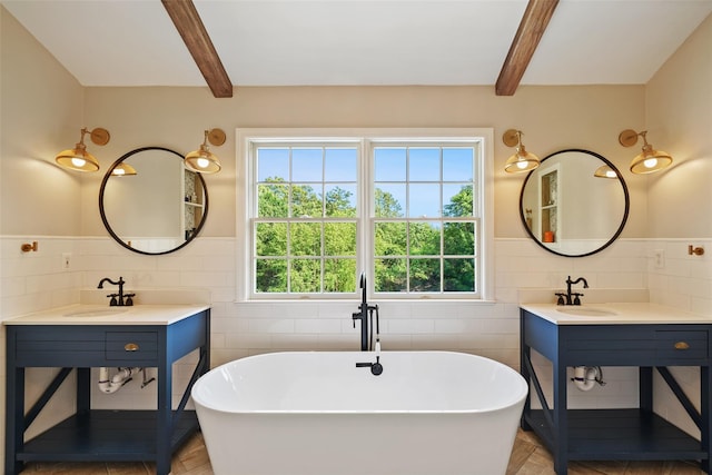 10 Inverness Ct, White Plains, NY 10605 - bathroom featuring tile walls, beamed ceiling, a freestanding bath, wainscoting, and two sinks