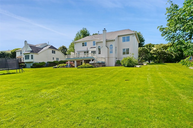 10 Inverness Ct, White Plains, NY 10605 - back of house with a trampoline, a lawn, a wooden deck, and a chimney