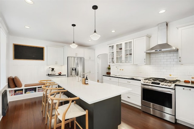 1223 Albany Post Rd, Croton-On-Hudson, NY 10520 - kitchen with appliances with stainless steel finishes, wall chimney exhaust hood, tasteful backsplash, dark wood-type flooring, and glass insert cabinets