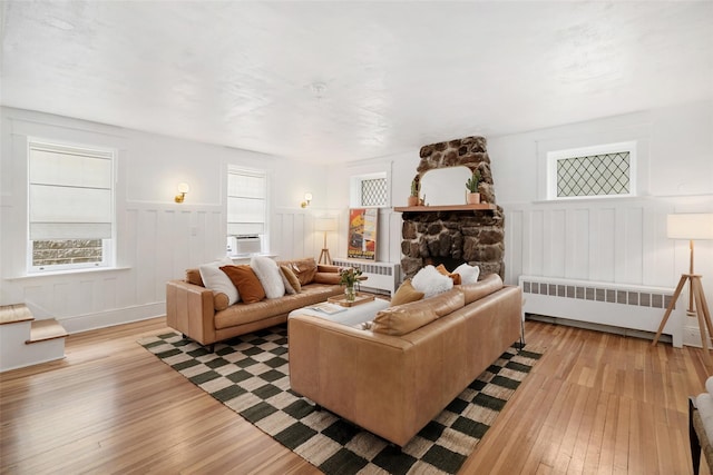 1223 Albany Post Rd, Croton-On-Hudson, NY 10520 - living area featuring radiator heating unit, light wood finished floors, wainscoting, cooling unit, and a decorative wall