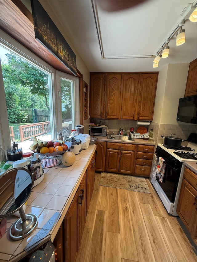 1016 Howells Rd, Bay Shore, NY 11706 - kitchen with gas range oven, tile counters, black microwave, and brown cabinets
