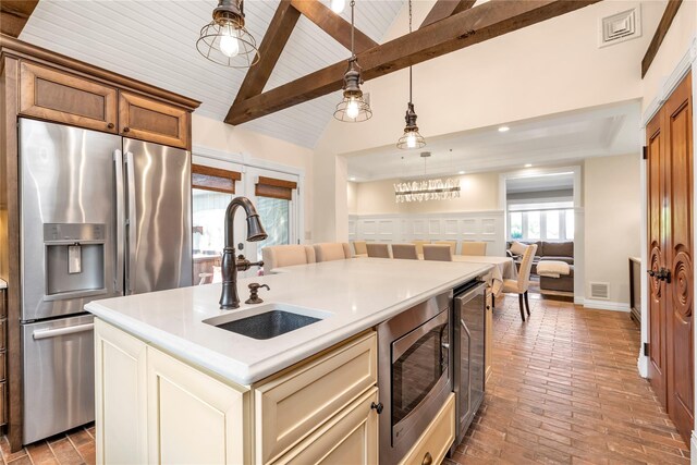 95 Falmouth Pl, Albertson, NY 11507 - kitchen with appliances with stainless steel finishes, brick flooring, hanging light fixtures, light countertops, and a center island with sink