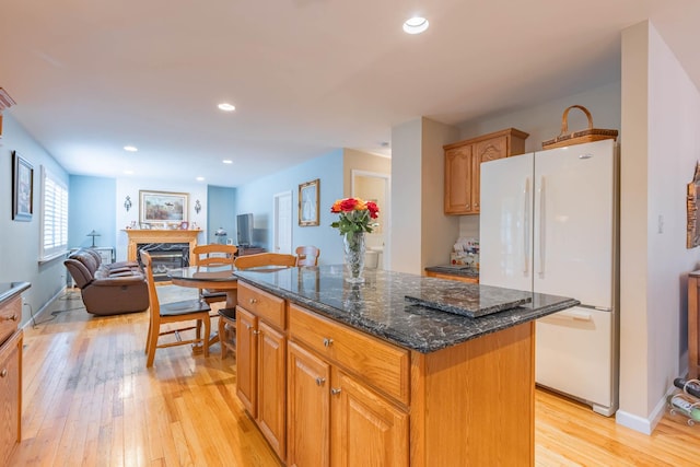 195 Bridle Way, Oakdale, NY 11769 - kitchen with freestanding refrigerator, light wood-style flooring, a premium fireplace, a kitchen island, and dark stone counters