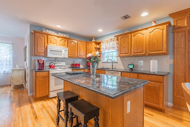 195 Bridle Way, Oakdale, NY 11769 - kitchen featuring white appliances, light wood finished floors, a kitchen island, backsplash, and dark stone countertops