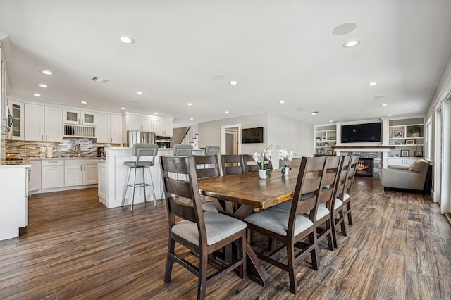 26 Island Pkwy N, Island Park, NY 11558 - dining space featuring a glass covered fireplace, dark wood finished floors, recessed lighting, and stairs