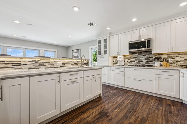 26 Island Pkwy N, Island Park, NY 11558 - kitchen with stainless steel microwave, decorative backsplash, dark wood-type flooring, healthy amount of natural light, and recessed lighting