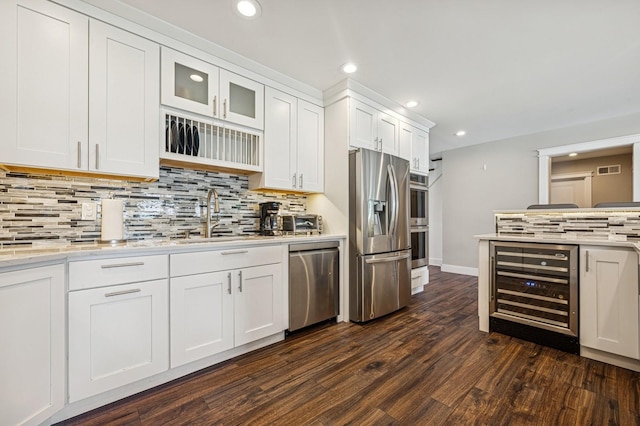 26 Island Pkwy N, Island Park, NY 11558 - kitchen with appliances with stainless steel finishes, wine cooler, dark wood-style flooring, decorative backsplash, and white cabinets