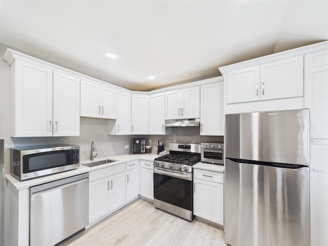 18 Huron St, Port Jefferson Station, NY 11776 - kitchen with stainless steel appliances, under cabinet range hood, white cabinets, light countertops, and light wood-style flooring