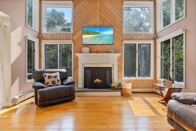 48 Orchard Hill Rd, Carmel, NY 10512 - living room with a towering ceiling, a baseboard radiator, healthy amount of natural light, a lit fireplace, and wood-type flooring