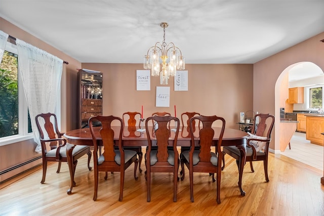 48 Orchard Hill Rd, Carmel, NY 10512 - dining room with arched walkways, a chandelier, baseboard heating, and light wood-style floors