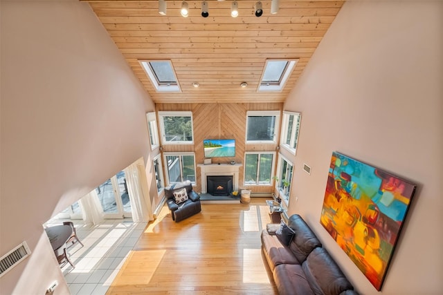 48 Orchard Hill Rd, Carmel, NY 10512 - living area with a skylight, wooden ceiling, high vaulted ceiling, a lit fireplace, and light wood-style flooring