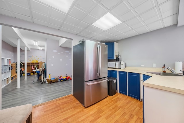 48 Orchard Hill Rd, Carmel, NY 10512 - kitchen featuring blue cabinets, freestanding refrigerator, light wood-style flooring, light countertops, and white microwave
