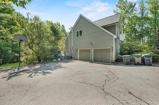48 Orchard Hill Rd, Carmel, NY 10512 - view of side of property featuring asphalt driveway, an attached garage, and a shingled roof