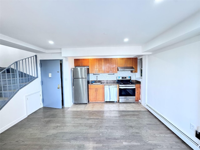 43-18 Robinson Unit 7C, Flushing, NY 11355 - kitchen featuring appliances with stainless steel finishes, baseboard heating, under cabinet range hood, light wood-style floors, and backsplash