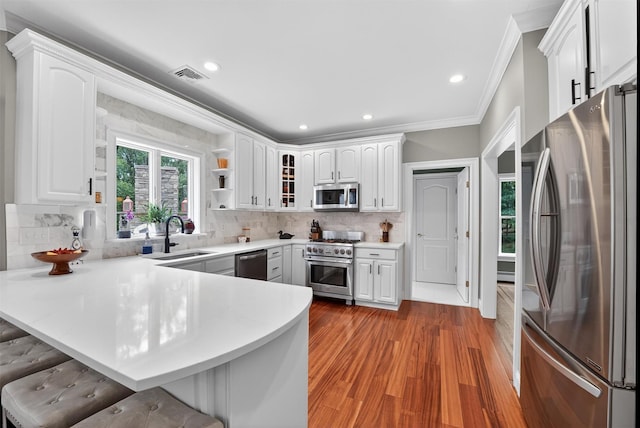 2300 State Route 207, Rock Tavern, NY 12575 - kitchen with stainless steel appliances, a peninsula, a kitchen bar, light wood-type flooring, and crown molding
