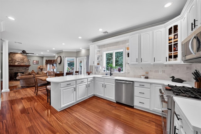 2300 State Route 207, Rock Tavern, NY 12575 - kitchen featuring appliances with stainless steel finishes, a peninsula, a fireplace, light wood-type flooring, and crown molding