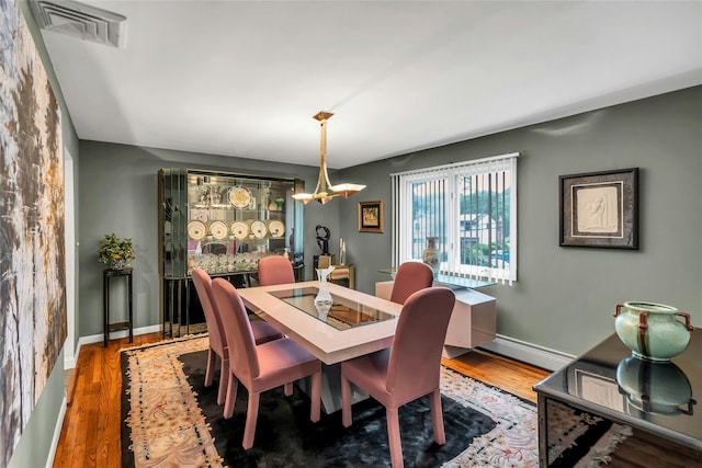 185 Harvard Dr, Plainview, NY 11803 - dining area featuring a baseboard heating unit, wood finished floors, and a chandelier