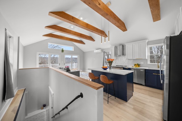 13 Ripley Rd, Patterson, NY 12563 - kitchen with stainless steel appliances, wall chimney exhaust hood, light wood-type flooring, a breakfast bar, and light countertops