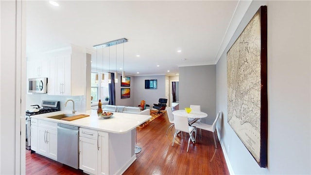 1133 Midland Ave Unit 4C, Bronxville, NY 10708 - kitchen featuring stainless steel appliances, open floor plan, white cabinets, dark wood finished floors, and ornamental molding