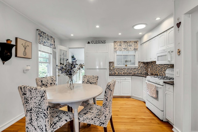 15 Robbins Ave, Islip, NY 11751 - kitchen featuring white appliances, dark countertops, light wood-style flooring, tasteful backsplash, and white cabinetry
