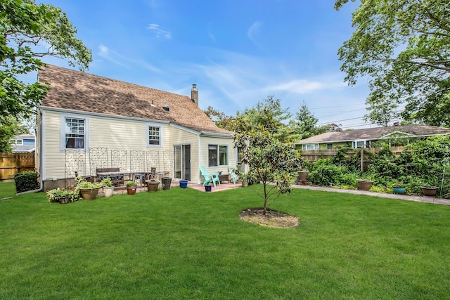 15 Robbins Ave, Islip, NY 11751 - back of property featuring a fenced backyard, a chimney, a patio, and a shingled roof