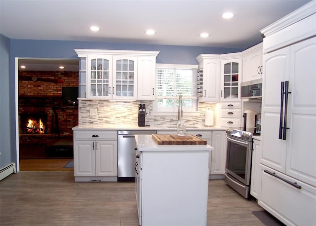 4 Bowman Ln, Commack, NY 11725 - kitchen featuring stainless steel appliances, light countertops, decorative backsplash, a kitchen island, and light wood-type flooring
