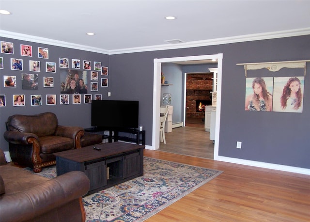 4 Bowman Ln, Commack, NY 11725 - living room with wood finished floors, ornamental molding, a baseboard radiator, a brick fireplace, and recessed lighting