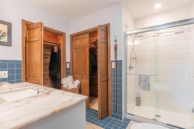 2136 Rte 55, Lagrangeville, NY 12540 - full bathroom featuring vanity, a walk in closet, a stall shower, tile walls, and tile patterned flooring