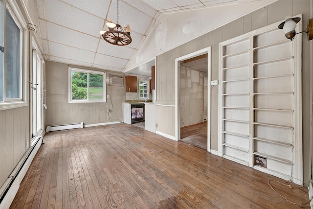 9 Mimosa St, Lake Peekskill, NY 10537 - unfurnished living room featuring a baseboard radiator, hardwood / wood-style floors, wooden walls, vaulted ceiling, and a chandelier