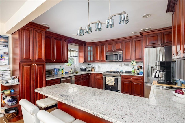 755 E Chester St, Long Beach, NY 11561 - kitchen with appliances with stainless steel finishes, dark brown cabinets, a peninsula, backsplash, and light stone countertops