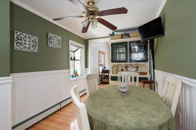 25 December Walk, Long Beach, NY 11561 - dining space featuring baseboard heating, a wainscoted wall, a ceiling fan, wood finished floors, and ornamental molding