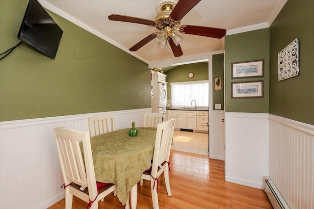 25 December Walk, Long Beach, NY 11561 - dining area featuring baseboard heating, a wainscoted wall, stacked washing machine and dryer, ceiling fan, and light wood-type flooring