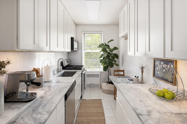 29 Abeel Unit 6C, Yonkers, NY 10705 - kitchen with radiator, appliances with stainless steel finishes, decorative backsplash, light stone countertops, and white cabinetry