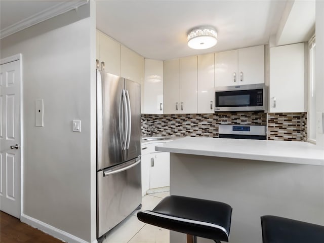 61-25 98th St Unit 2H, Rego Park, NY 11374 - kitchen featuring appliances with stainless steel finishes, light countertops, tasteful backsplash, and a peninsula