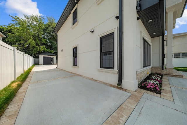 71 Cedar St, Hicksville, NY 11801 - view of side of property with an outbuilding, a detached garage, stucco siding, stone siding, and a patio