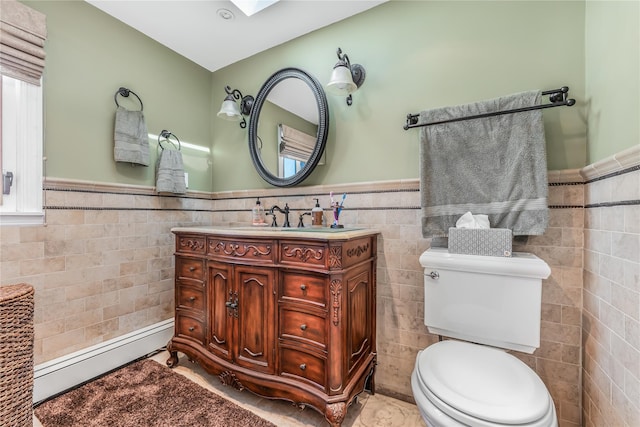 99 Stone Ln, Levittown, NY 11756 - bathroom featuring tile walls, wainscoting, vanity, baseboard heating, and a skylight
