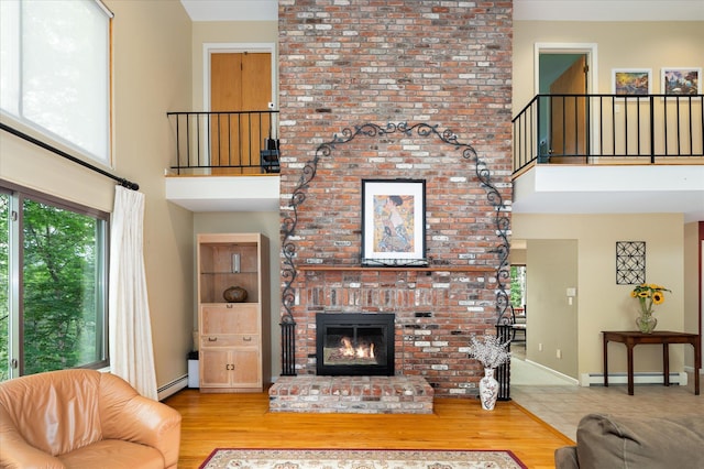 35 David Rd, Somers, NY 10589 - living area with baseboard heating, a high ceiling, a baseboard heating unit, a brick fireplace, and wood finished floors