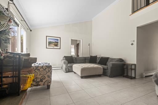 61 Sherwood Ct, Huntington, NY 11743 - living area featuring high vaulted ceiling, light tile patterned flooring, and a baseboard radiator