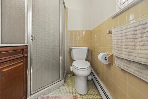 61 Sherwood Ct, Huntington, NY 11743 - full bath featuring a shower stall, tile walls, tile patterned flooring, baseboard heating, and vanity