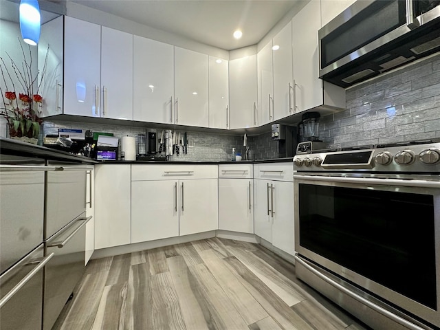 87-14 57th Rd Unit 1A, Elmhurst, NY 11373 - kitchen with stainless steel appliances, white cabinetry, light wood-type flooring, decorative backsplash, and recessed lighting