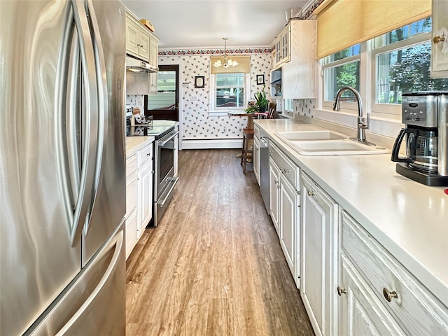 222 Beechwood Ave, Poughkeepsie, NY 12601 - kitchen featuring appliances with stainless steel finishes, wood finished floors, wallpapered walls, healthy amount of natural light, and light countertops