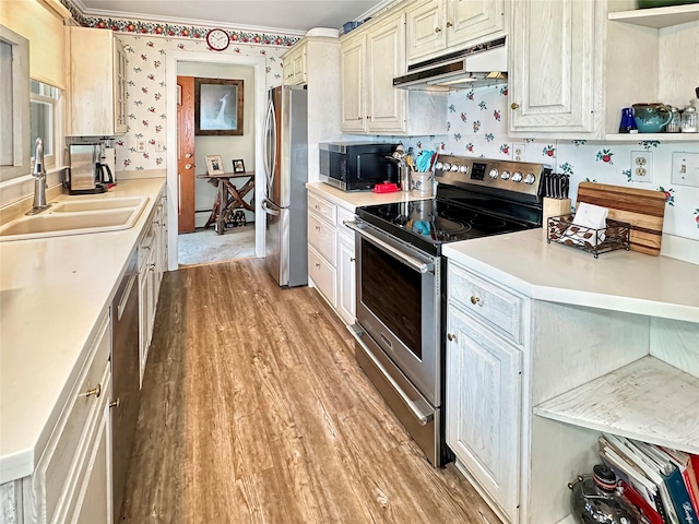 222 Beechwood Ave, Poughkeepsie, NY 12601 - kitchen with appliances with stainless steel finishes, under cabinet range hood, light countertops, light wood-type flooring, and crown molding