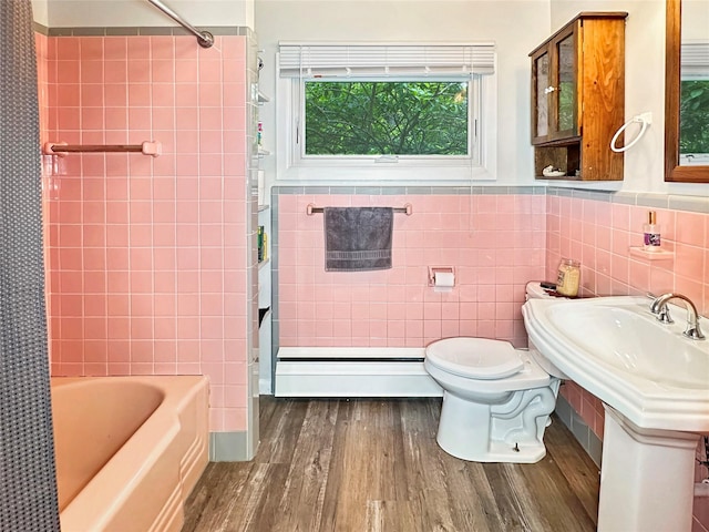 222 Beechwood Ave, Poughkeepsie, NY 12601 - full bathroom featuring a baseboard heating unit, wood finished floors, tile walls, shower / bath combo with shower curtain, and a wainscoted wall