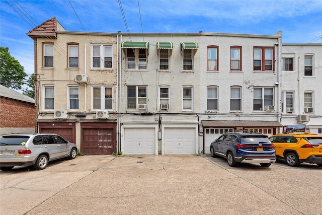 4204 64th St, Woodside, NY 11377 - view of front facade with a garage, brick siding, driveway, and cooling unit