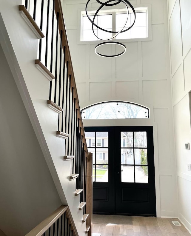96A Calvin Ave, Syosset, NY 11791 - entrance foyer with stairway, french doors, plenty of natural light, a decorative wall, and wood finished floors